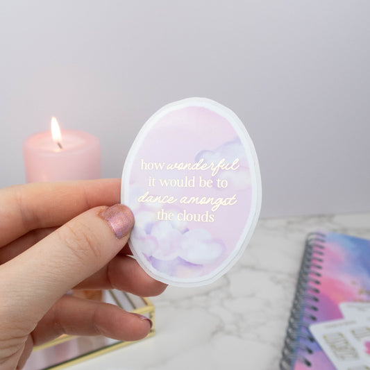 Hand holding a small round object with text, next to a lit pink candle on a light gray background