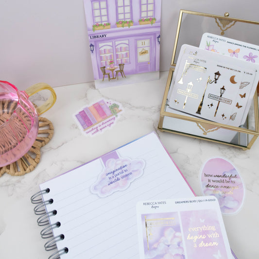 Stationery items including a notebook, stickers, and a card on a light surface.