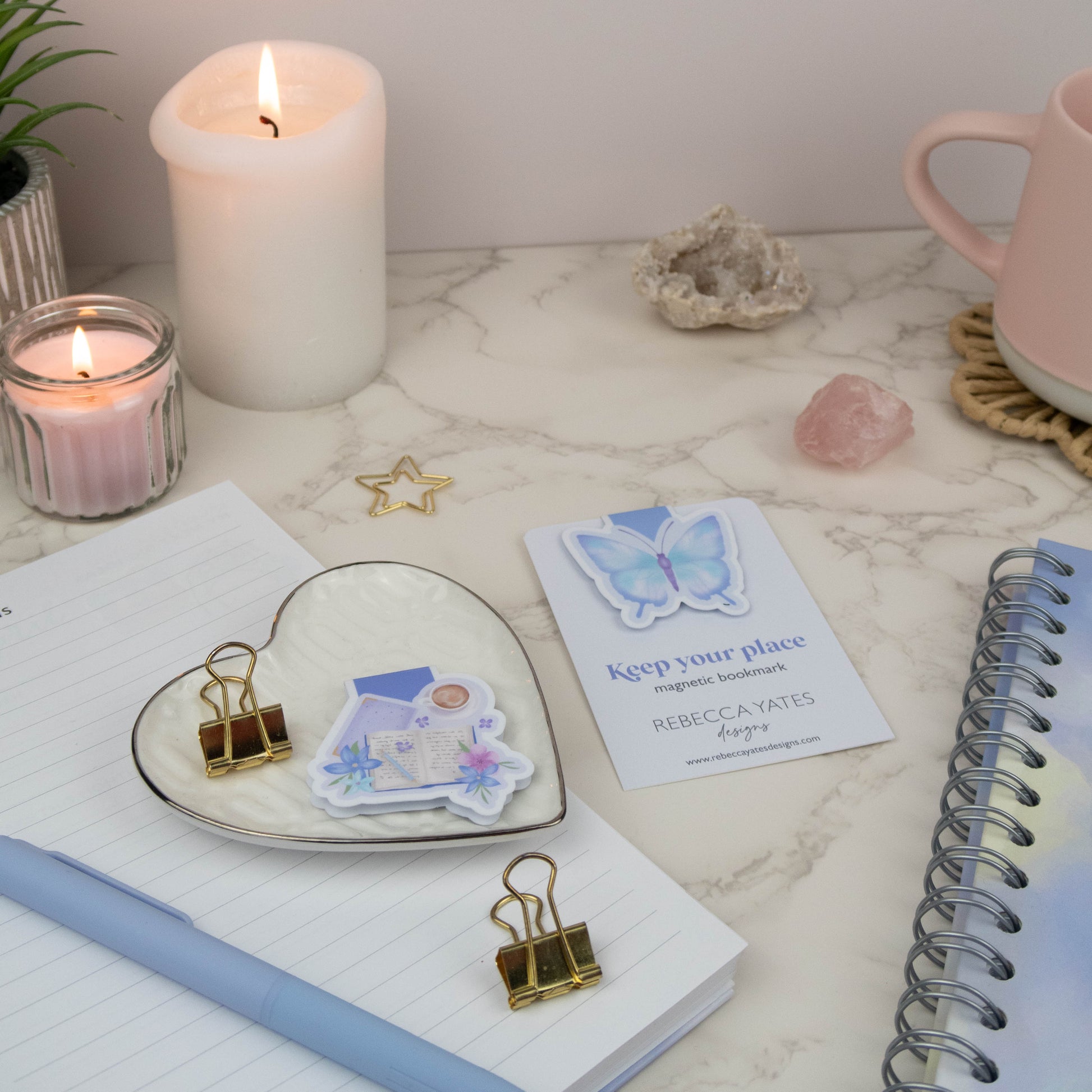Magnetic Bookmark displayed alongside candles, a pink mug, and a spiral-bound planner on a cozy desk setup.