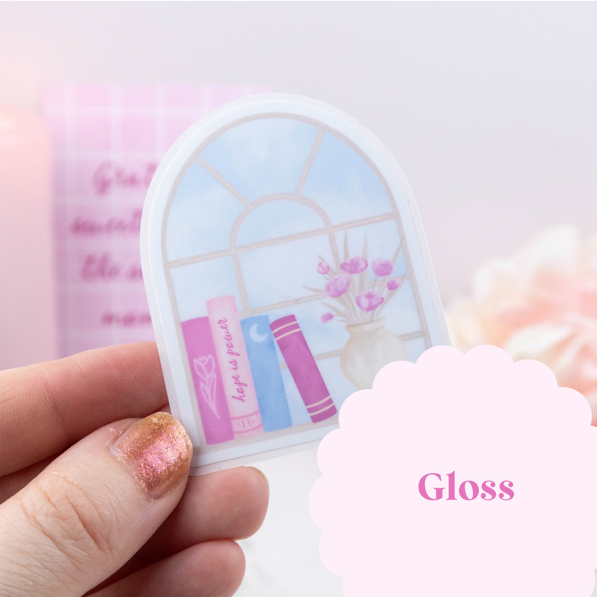 Hand holding a small round mirror with a decorative design on a light pink background