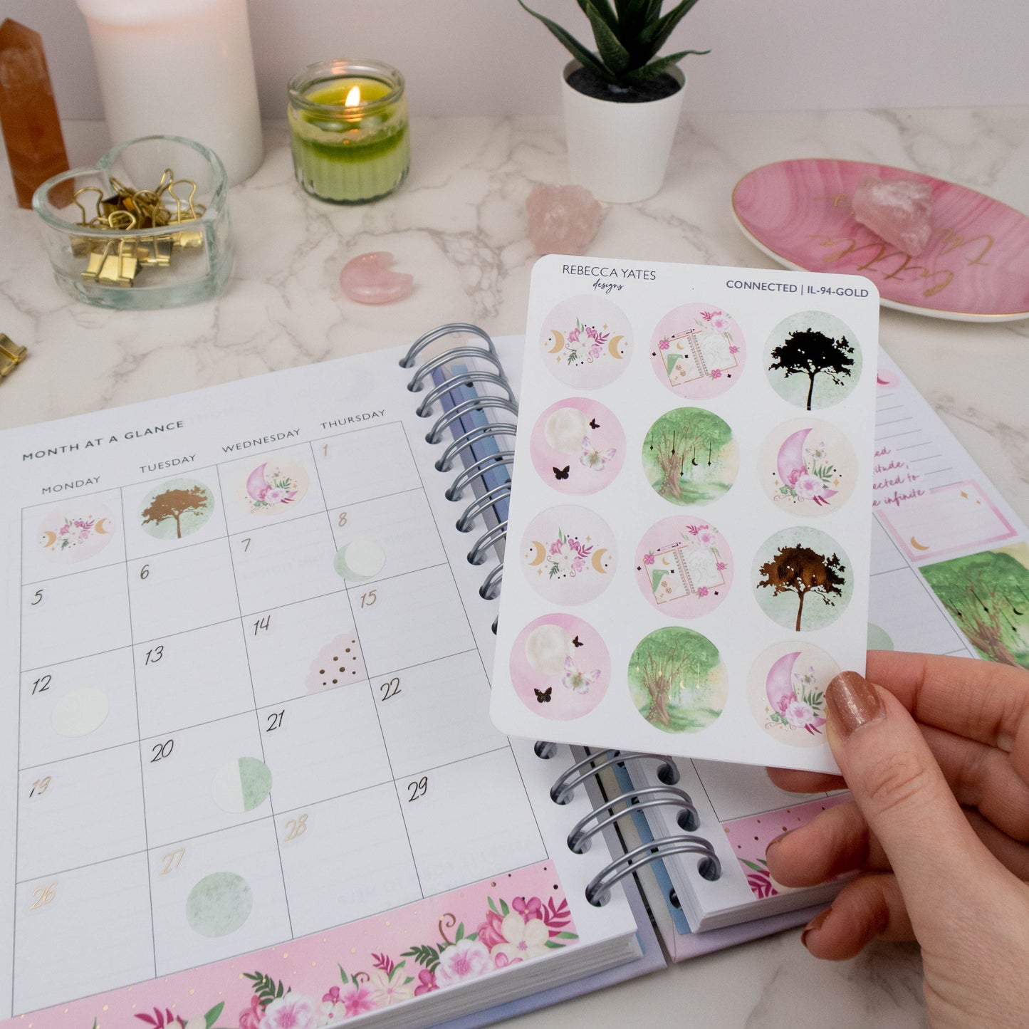 Earth Element Decorative Circle Sticker Sheet featuring woodland trees, moons, florals, and calming nature-inspired designs. Displayed in a monthly overview planner. 