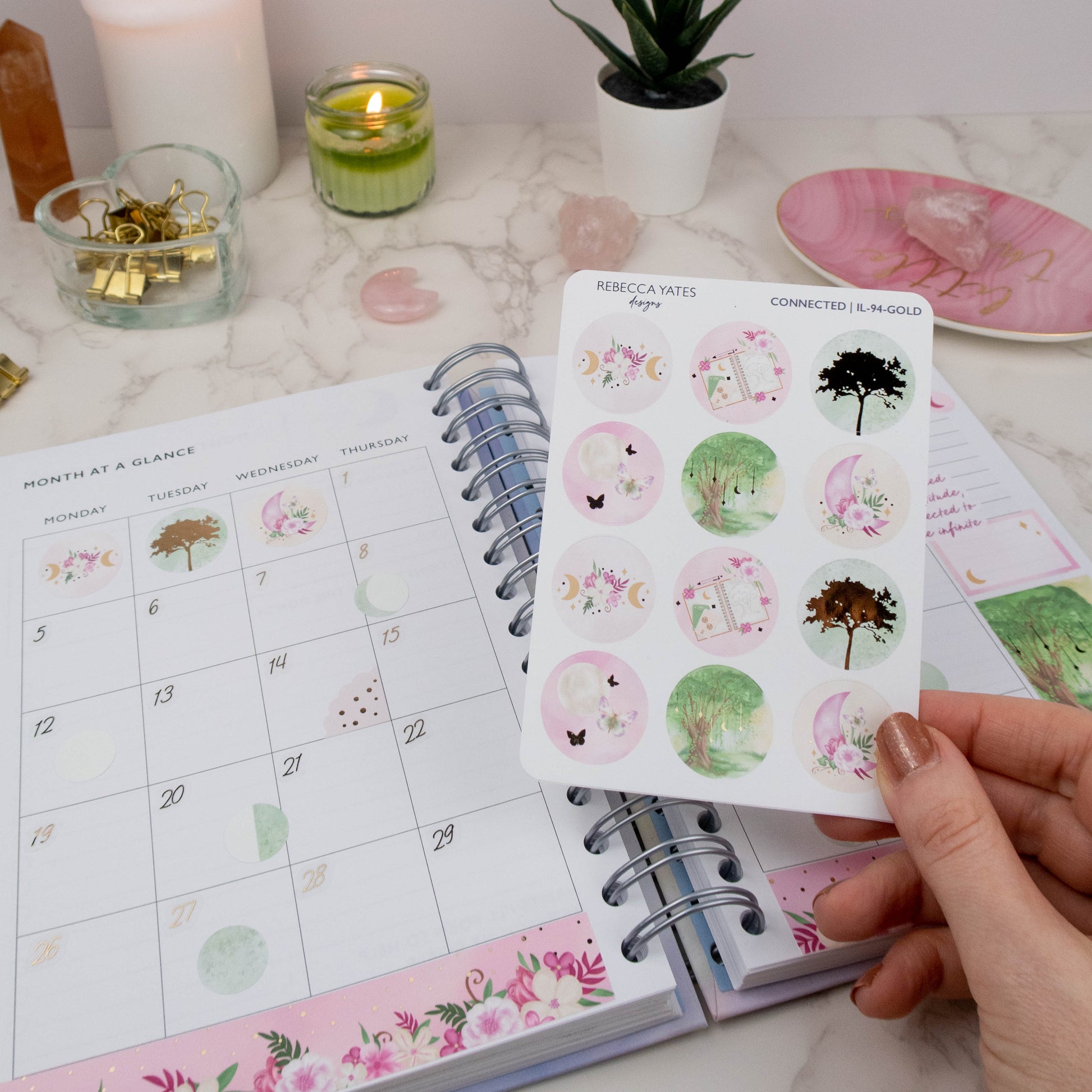 Earth Element Decorative Circle Sticker Sheet featuring woodland trees, moons, florals, and calming nature-inspired designs. Displayed in a monthly overview planner. 