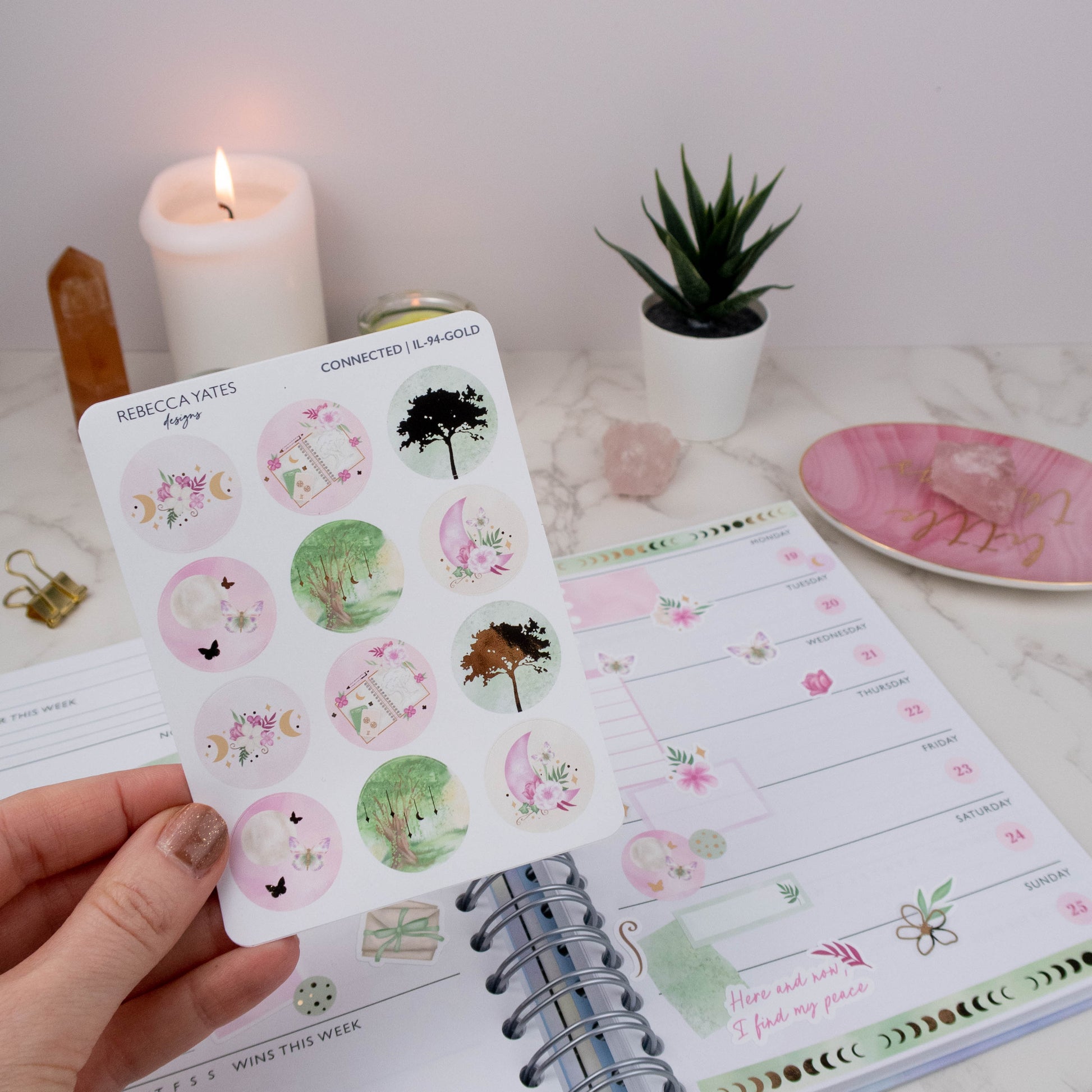 Earth Element Decorative Circle Sticker Sheet featuring woodland trees, moons, florals, and calming nature-inspired designs, displayed on a marble desk with a lit candle, planner, and decorative stationery items.